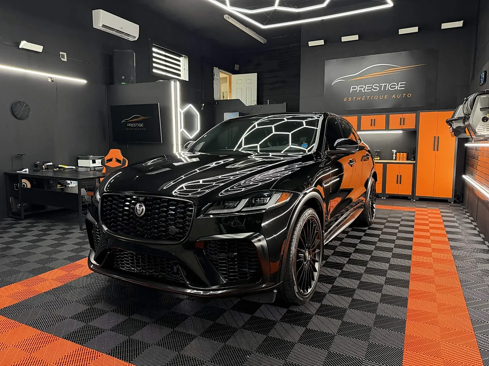 Jaguar F-Pace SVR noire sous l'éclairage hexagonal de l'atelier Prestige Esthétique Auto