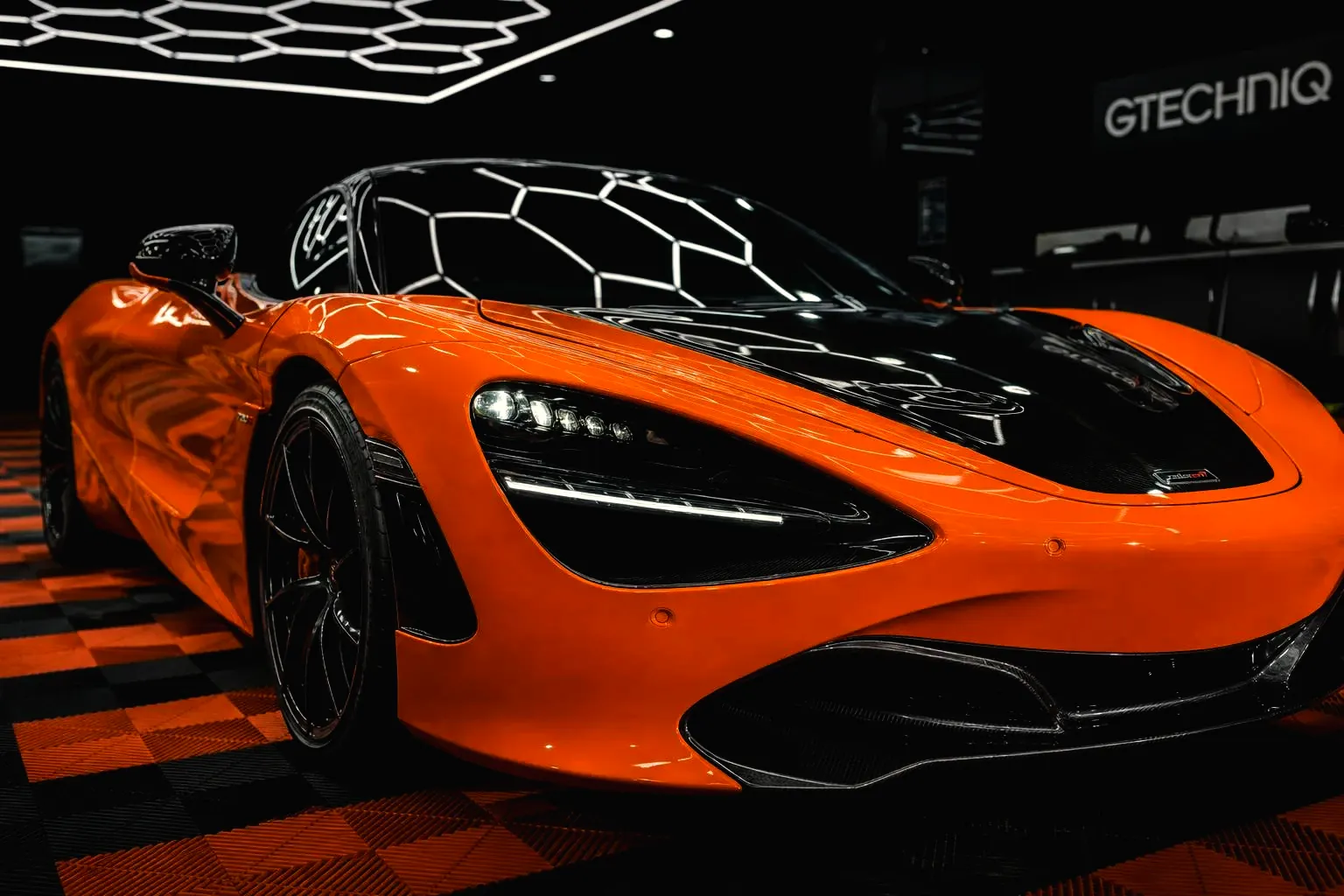 McLaren 720S orange et noir de trois quarts avant, après esthétique complète à l'atelier